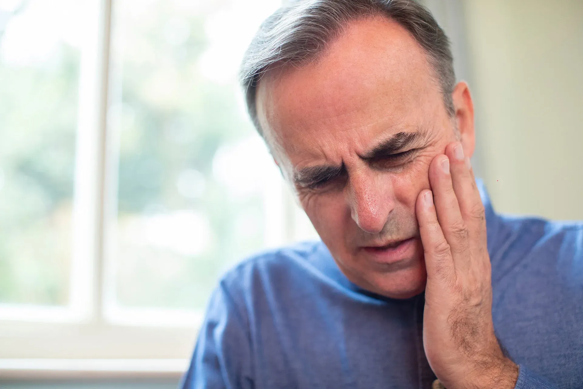 Man holding cheek due to dental emergency toothache