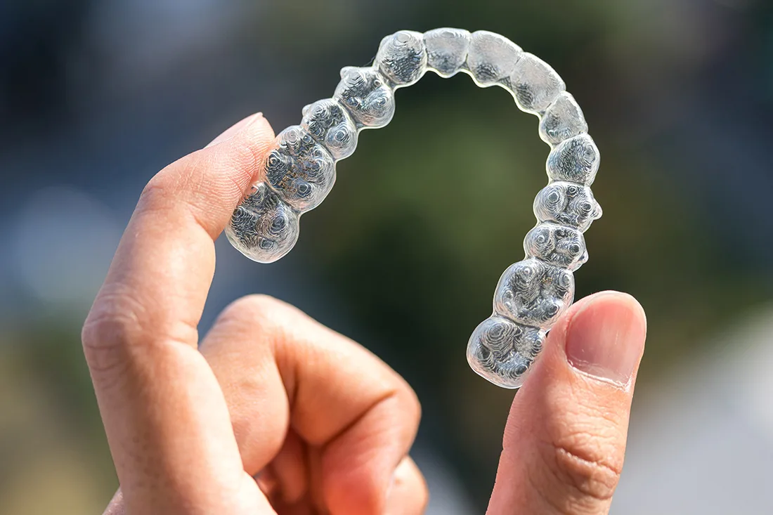 Hand holding a clear orthodontic aligner tray