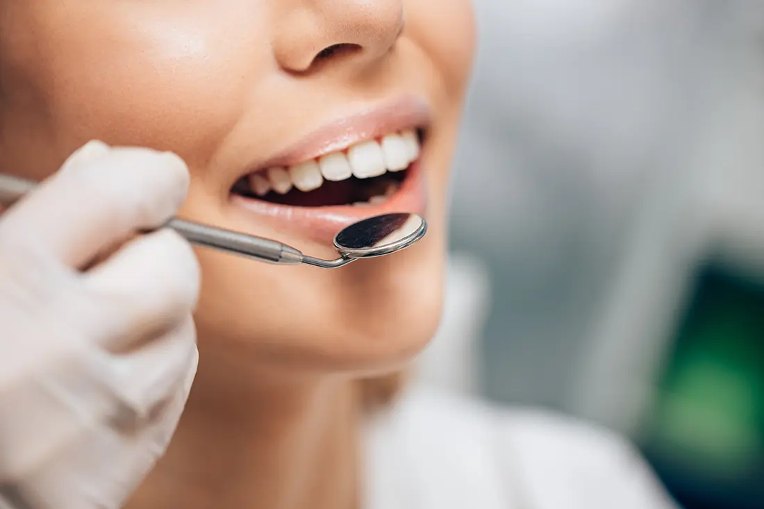 Dentist using a dental mirror during a cosmetic enameloplasty consultation