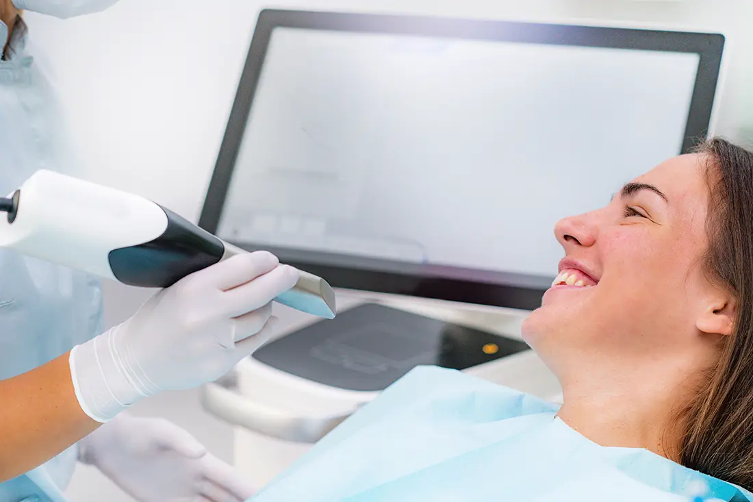 Smiling patient in a dental chair while a clinician uses a handheld digital scanner